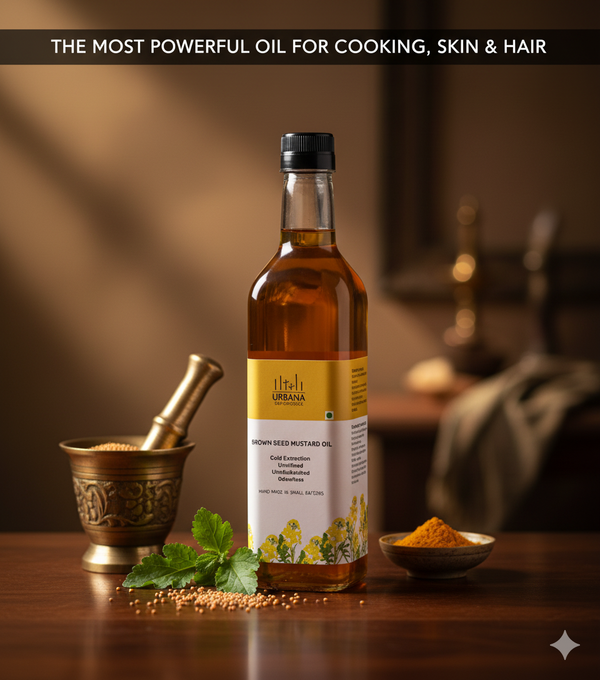 Urbana brown seed mustard oil placed with a brass mortar of mustard seeds, a bowl of turmeric and mint leaves on a wooden table in a softly lit kitchen setting.